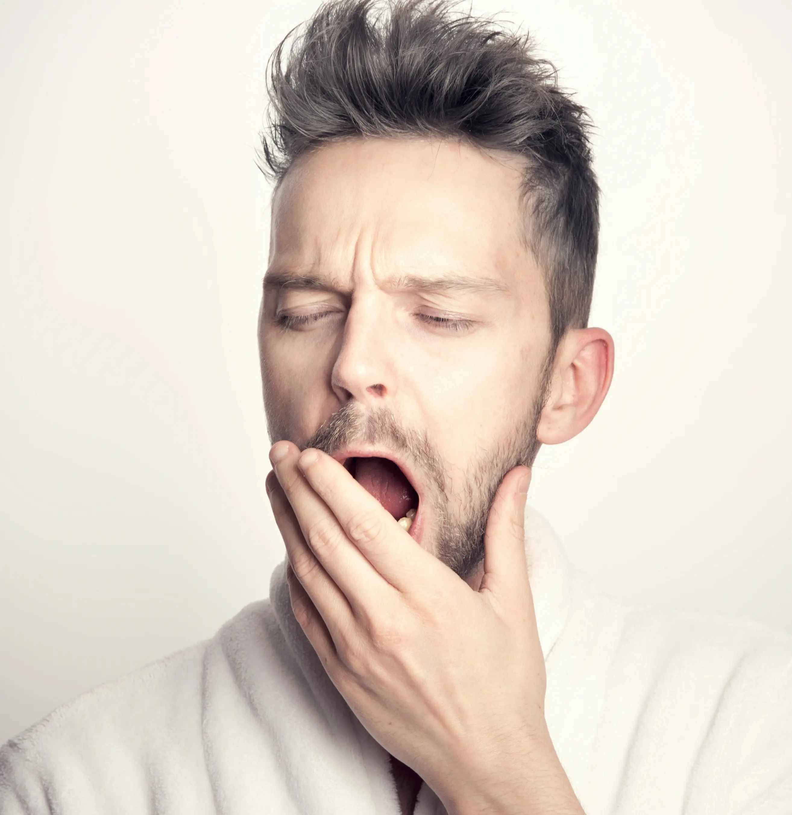 Man in white robe yawning
