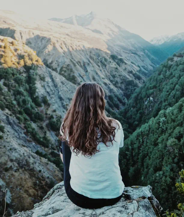 Back view of woman on mountain top looking at mountain range