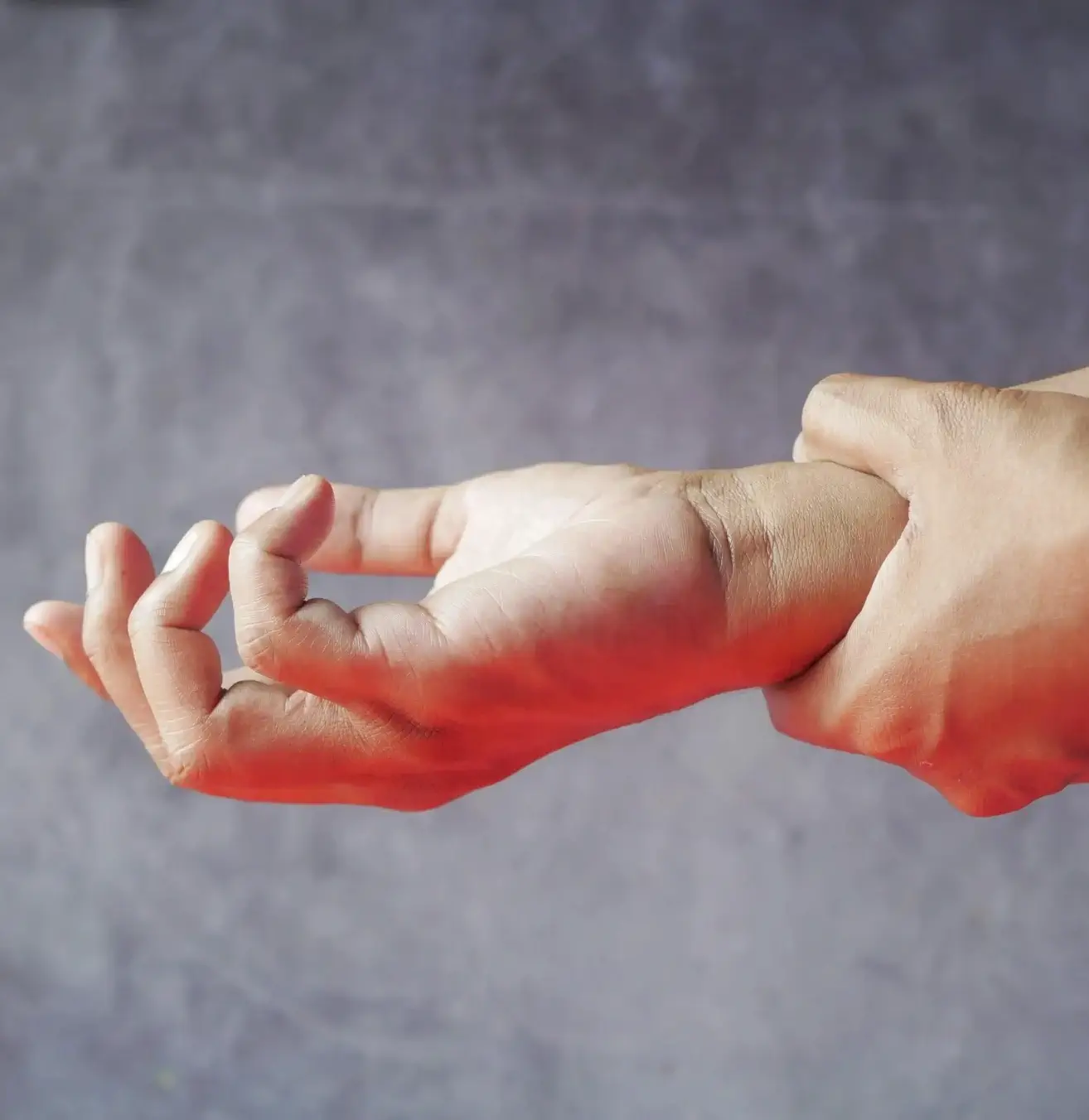 Seitliche Nahaufnahme einer Person, die ihr Handgelenk hält, grauer Hintergrund
