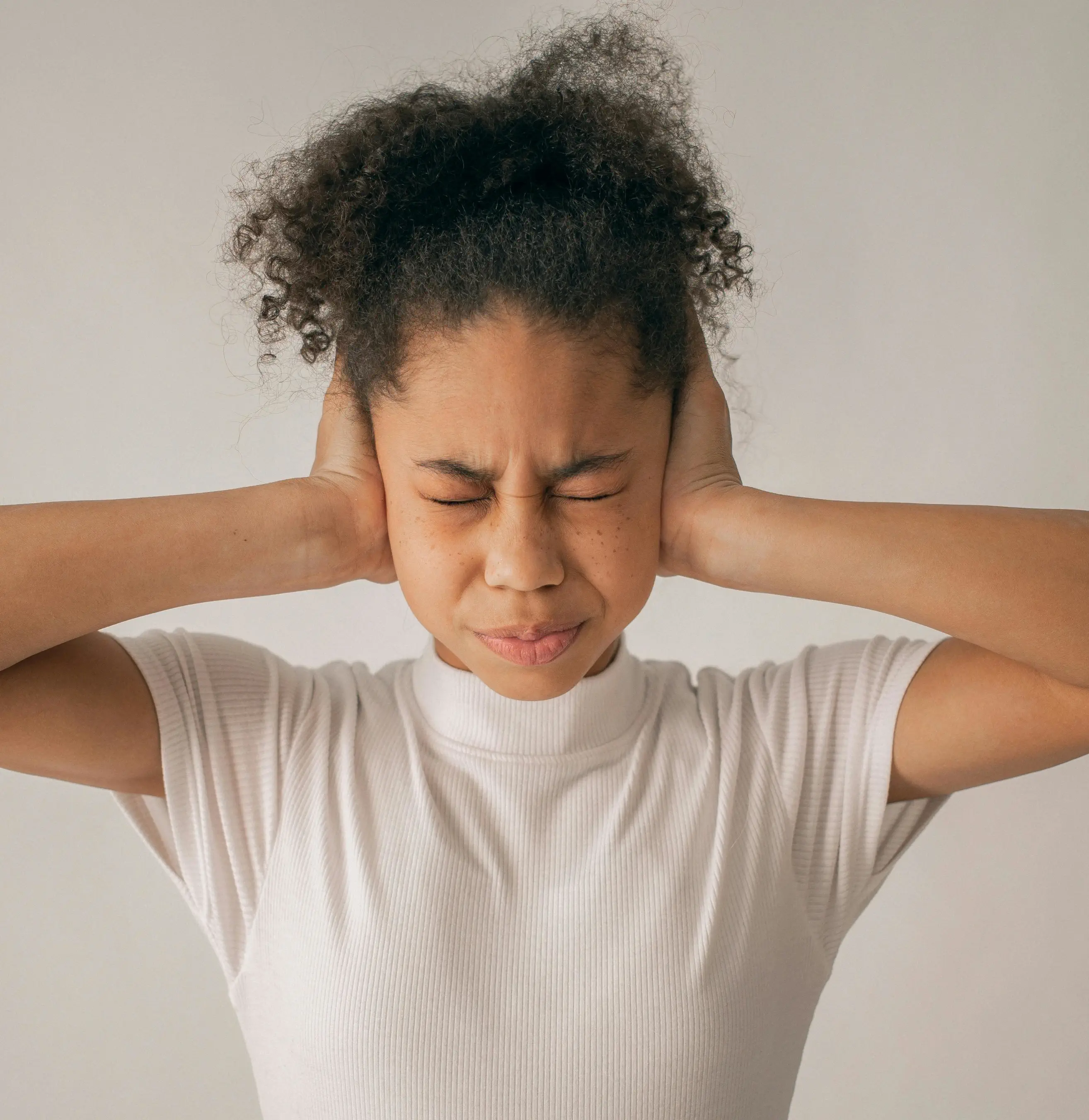 Young woman in pain covers ears.